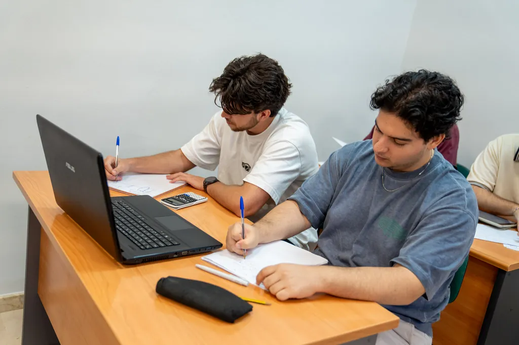 Mesa de estudio con apuntes, tableta y portátil durante la época de exámenes