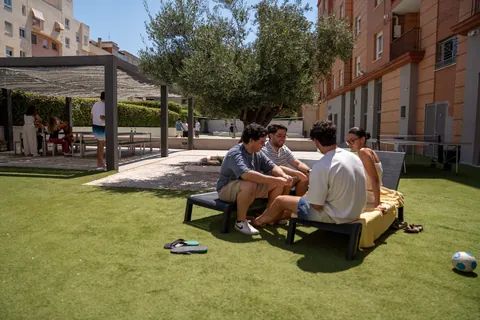 Grupo de residentes charlando en el jardín de la residencia junto al olivo