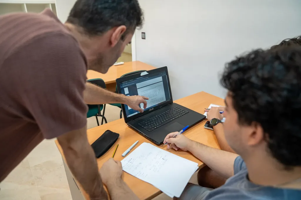 Tutor resolviendo dudas junto a un estudiante con su portátil